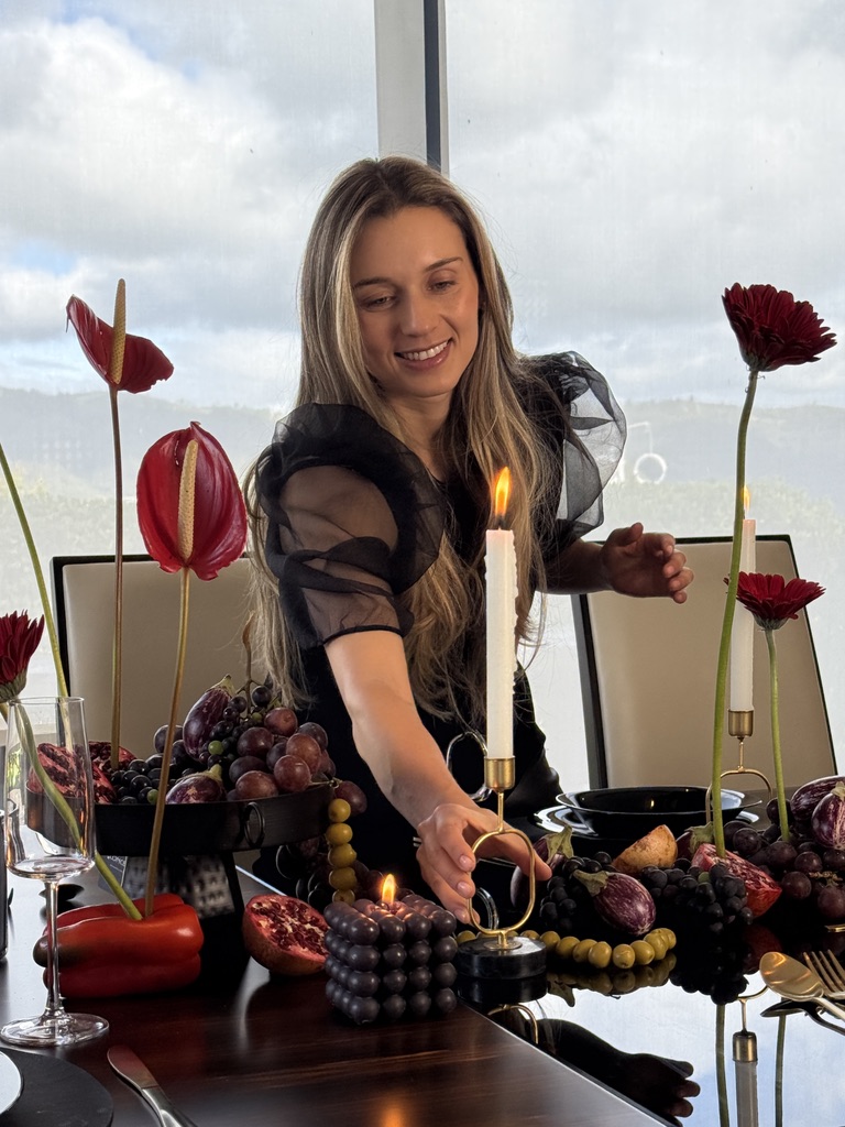 Encendido de velas sobre una mesa con anturios rojos, uvas y granadas