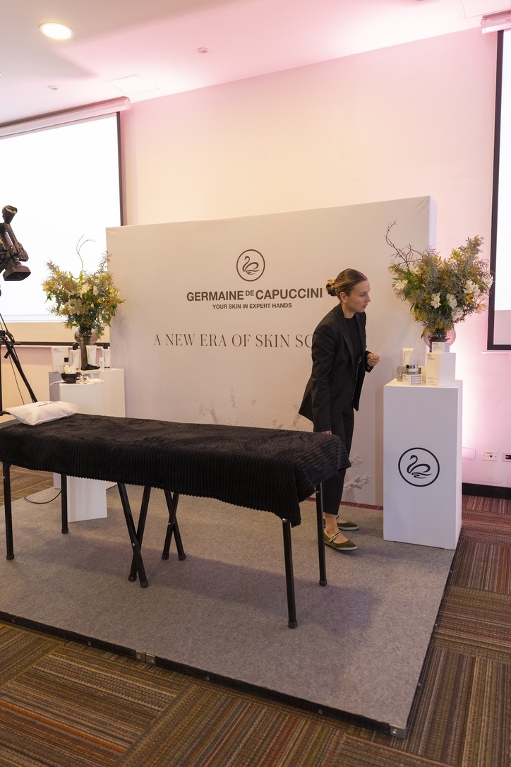 Backdrop de marca con pedestales y arreglos florales en el montaje del evento