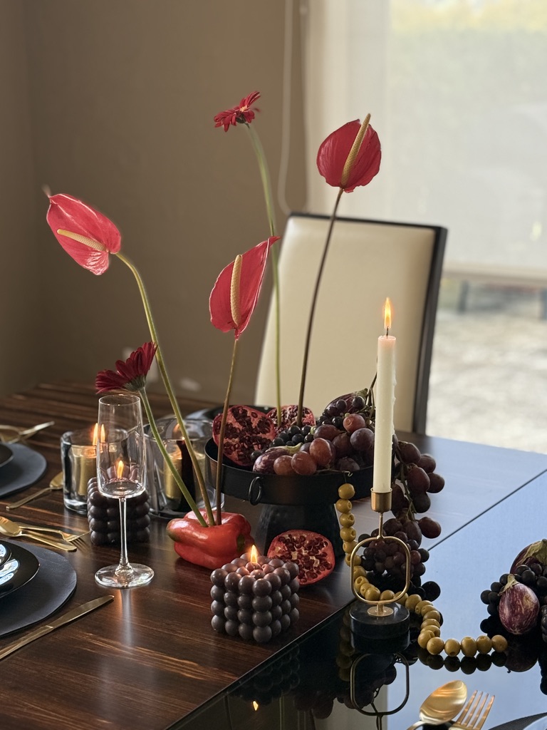 Centro de mesa con anturios rojos, frutas de temporada y velas encendidas