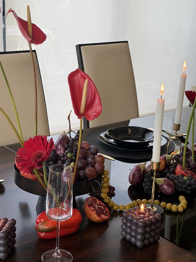 Detalle de menaje negro con cubiertos dorados, gerberas y candelabros