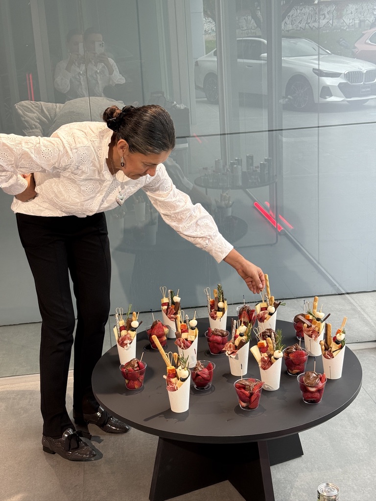 Anfitriona sirviendo conos de charcutería en el showroom de una marca automotriz