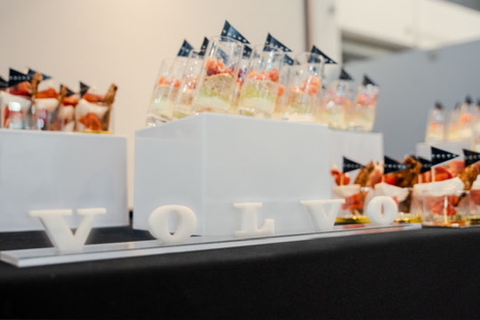 Mesa de bienvenida con letras de la marca y vasitos de pasabocas con banderines