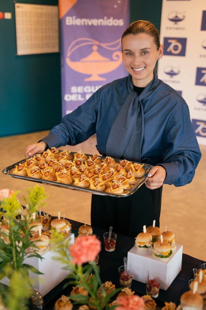 Anfitriona de Alta Mesa sirviendo una bandeja de mini hot dogs de autor en un evento corporativo