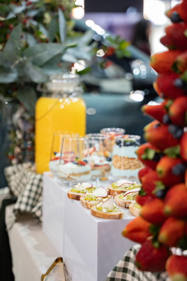 Yogures con granola, jugo de naranja, tostadas y torre de fresas en la mesa de brunch
